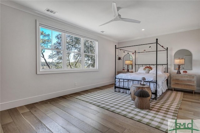 bedroom with baseboards, visible vents, a ceiling fan, wood finished floors, and crown molding