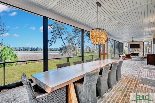 sunroom / solarium with wooden ceiling, a brick fireplace, and a chandelier