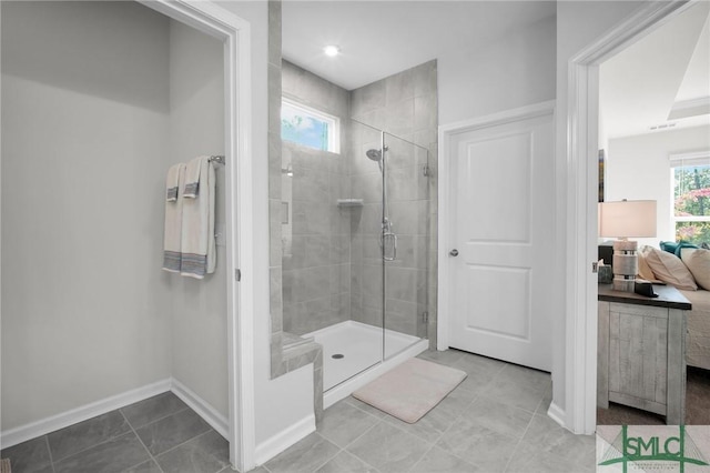 full bathroom featuring a stall shower, tile patterned flooring, baseboards, and ensuite bath