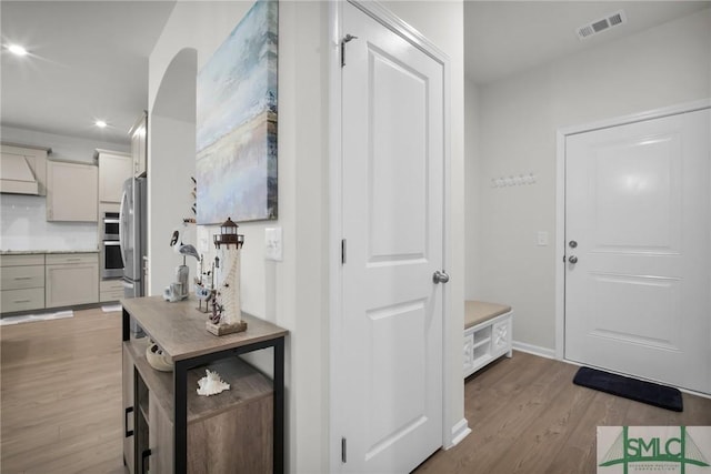 foyer entrance with visible vents, baseboards, and wood finished floors