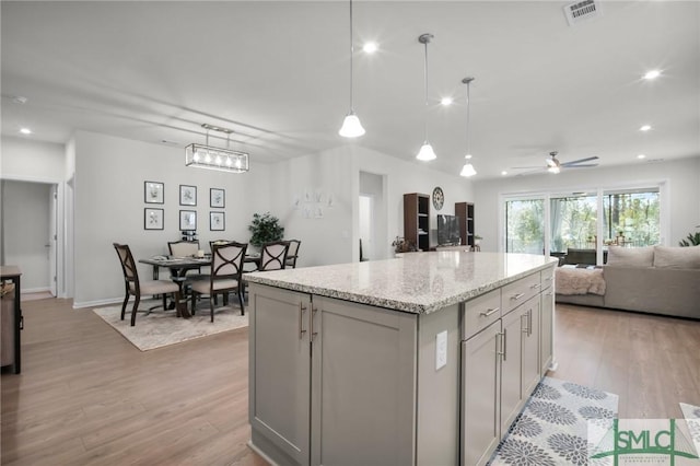 kitchen with visible vents, gray cabinetry, open floor plan, a kitchen island, and light wood-type flooring