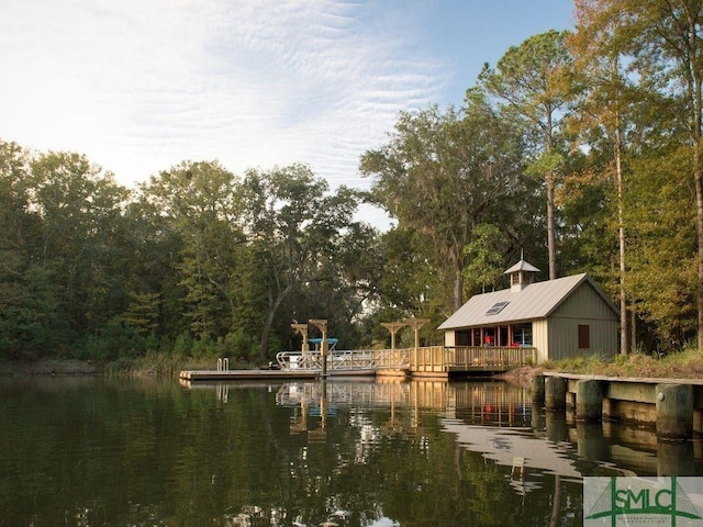 view of dock with a water view and a forest view