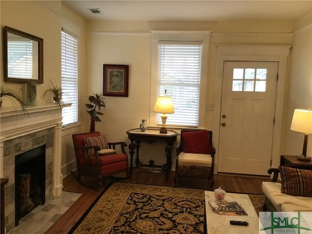 living room with a tiled fireplace, wood finished floors, and visible vents