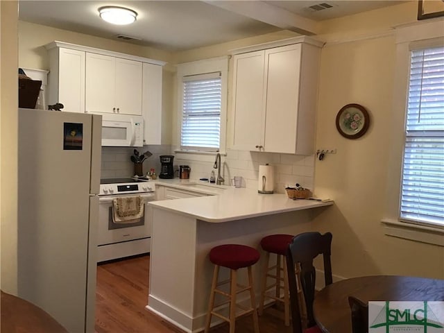 kitchen featuring white appliances, a sink, a peninsula, and decorative backsplash