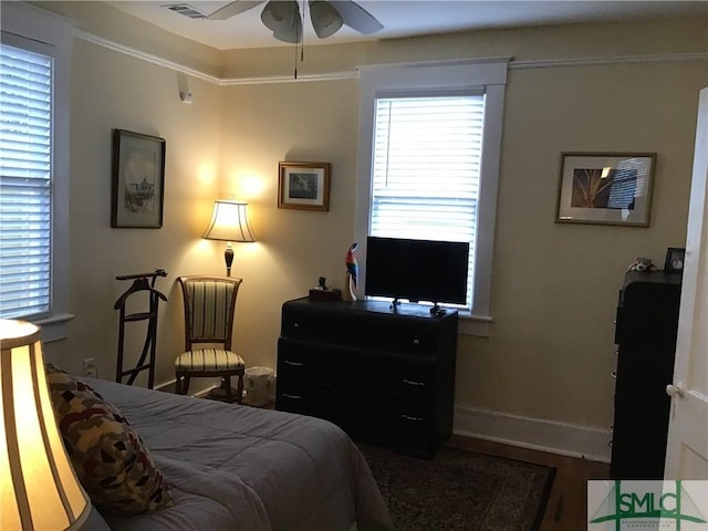 bedroom with baseboards, multiple windows, ornamental molding, and wood finished floors