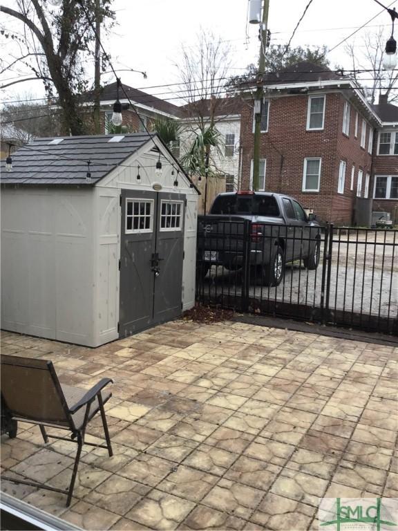 view of patio / terrace featuring fence, a storage unit, and an outdoor structure