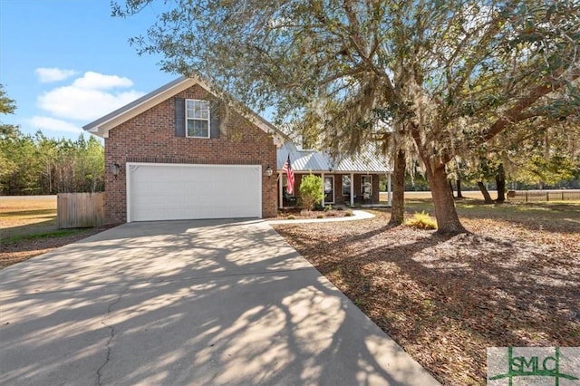 view of front facade with metal roof, a garage, brick siding, fence, and concrete driveway