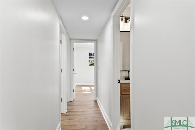 hallway featuring light wood-style flooring and baseboards