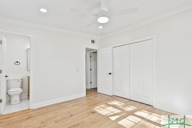 unfurnished bedroom with light wood-style flooring, visible vents, baseboards, ornamental molding, and a closet