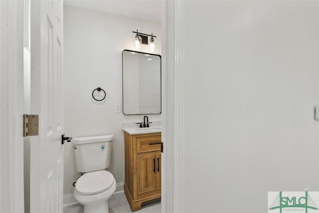 half bathroom featuring baseboards, vanity, and toilet