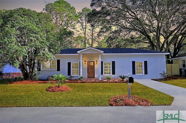 ranch-style house with a yard, brick siding, and driveway