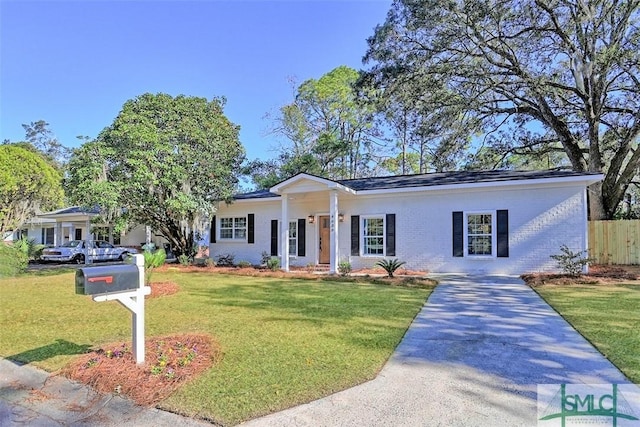 view of front of property featuring driveway, brick siding, a front yard, and fence