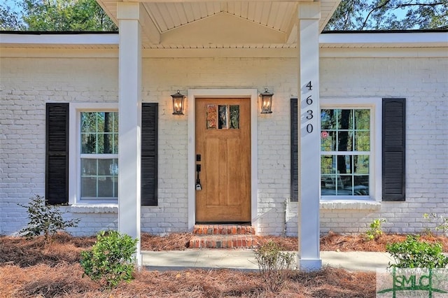 view of exterior entry featuring brick siding