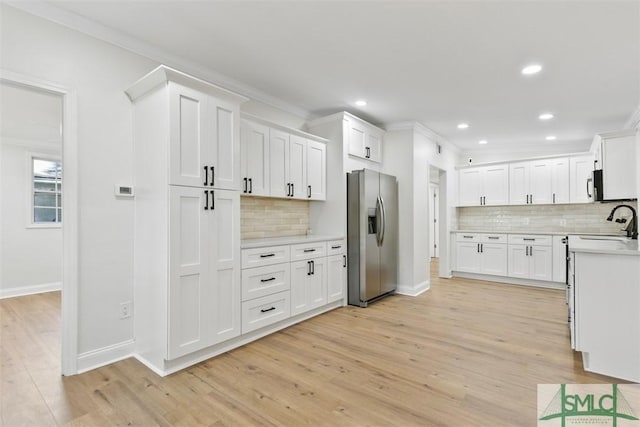 kitchen featuring crown molding, stainless steel refrigerator with ice dispenser, light countertops, light wood-style floors, and white cabinetry