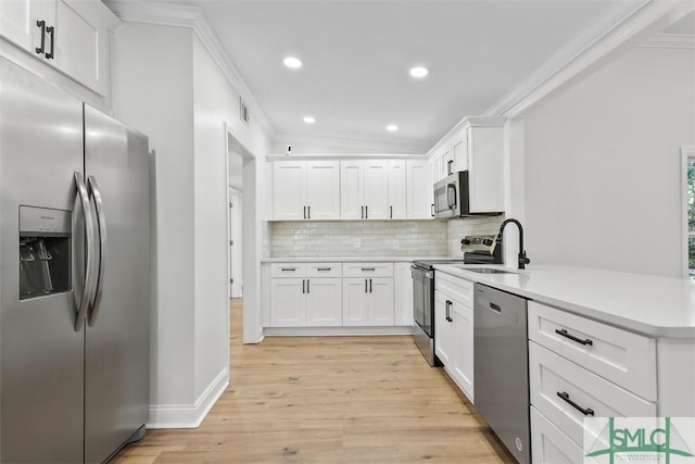 kitchen with light countertops, appliances with stainless steel finishes, ornamental molding, a sink, and a peninsula