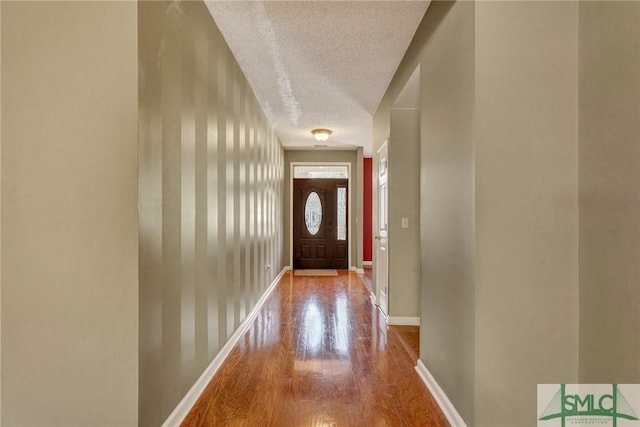 doorway featuring a textured ceiling, baseboards, and wood finished floors