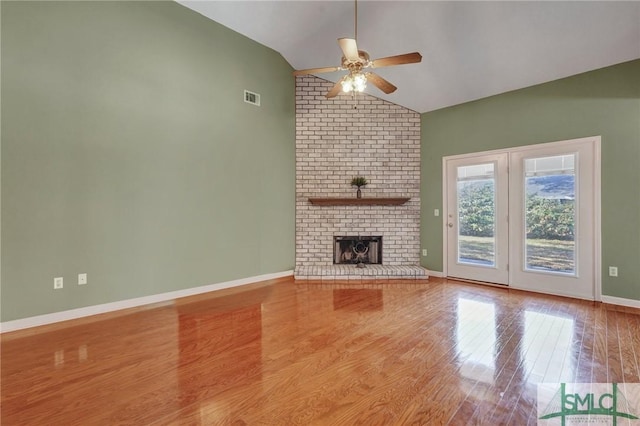 unfurnished living room featuring ceiling fan, wood finished floors, visible vents, baseboards, and a brick fireplace