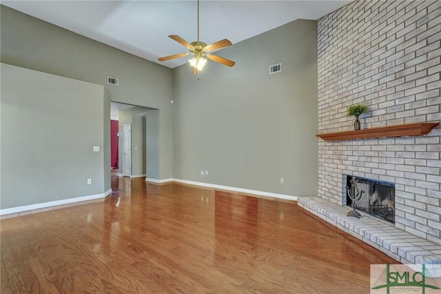 unfurnished living room with a fireplace, visible vents, a ceiling fan, and wood finished floors