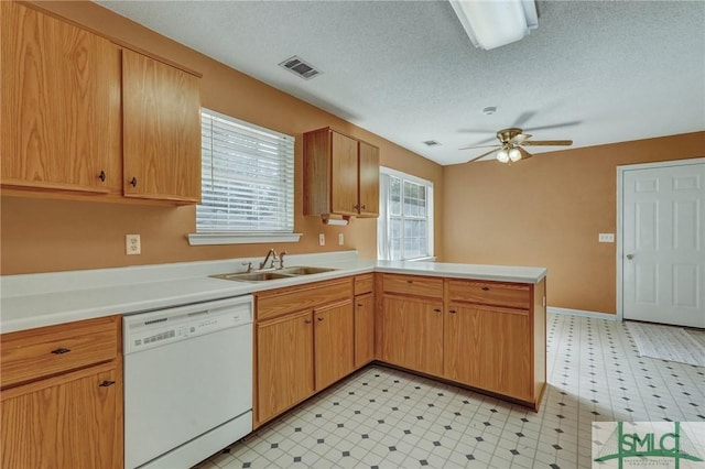 kitchen featuring light floors, visible vents, a sink, dishwasher, and a peninsula