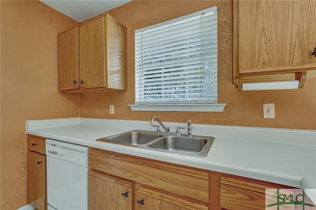 kitchen with light brown cabinets, light countertops, white dishwasher, and a sink