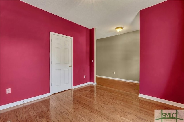 spare room with baseboards and wood finished floors