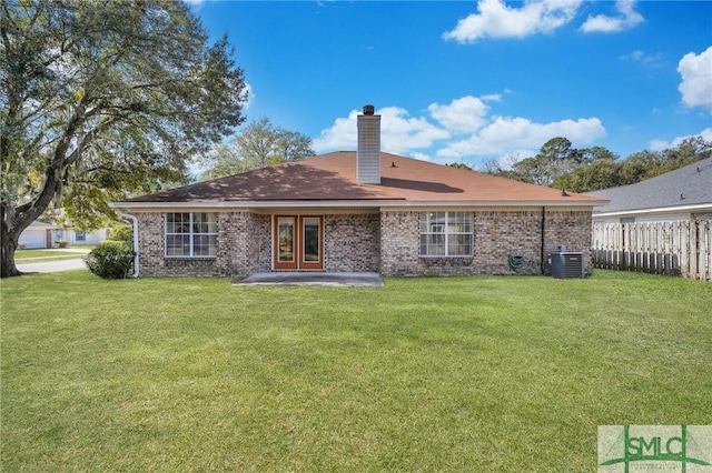 back of property with brick siding, fence, a chimney, and a lawn