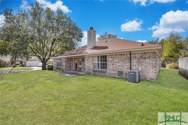 rear view of house with a lawn, cooling unit, and brick siding