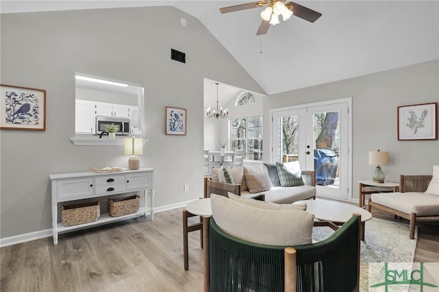 living room with light wood finished floors, baseboards, visible vents, french doors, and high vaulted ceiling