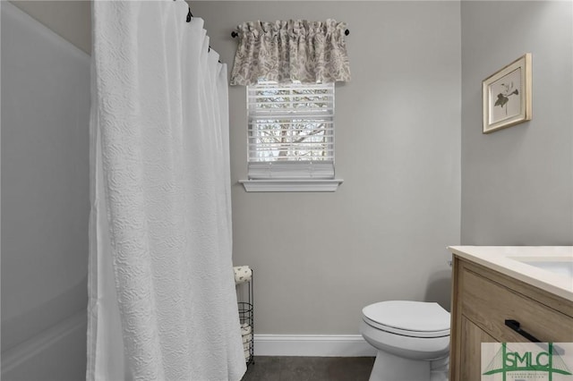 bathroom featuring a shower with shower curtain, baseboards, vanity, and toilet