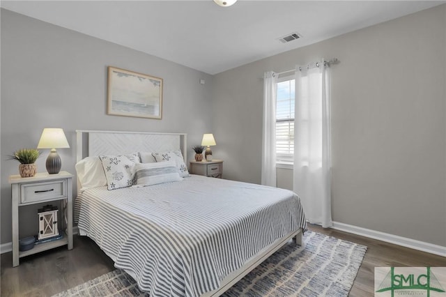 bedroom with baseboards, visible vents, and wood finished floors