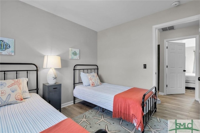 bedroom featuring visible vents, baseboards, and wood finished floors