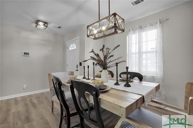 dining space with baseboards, visible vents, and wood finished floors