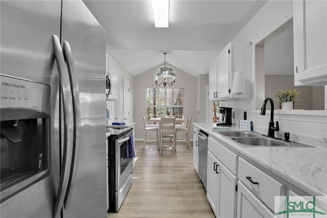 kitchen with stainless steel appliances, lofted ceiling, white cabinetry, and a sink