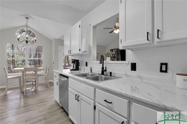 kitchen featuring lofted ceiling, stainless steel dishwasher, a sink, and white cabinets