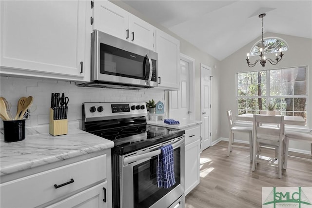 kitchen featuring lofted ceiling, stainless steel appliances, white cabinetry, backsplash, and an inviting chandelier