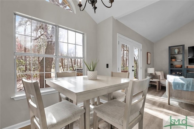 dining area with lofted ceiling, plenty of natural light, light wood-type flooring, and an inviting chandelier