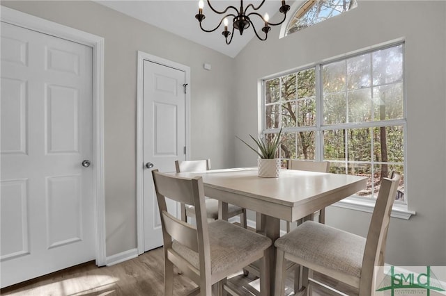 dining area featuring lofted ceiling, baseboards, a notable chandelier, and wood finished floors