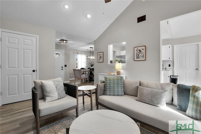 living room with high vaulted ceiling, wood finished floors, visible vents, and recessed lighting