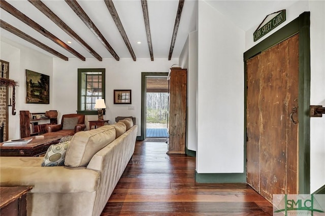 living area featuring dark wood-type flooring, beam ceiling, and a healthy amount of sunlight