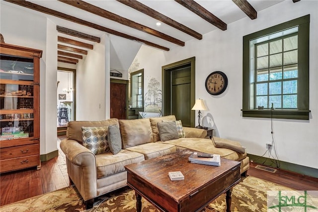 living area featuring lofted ceiling with beams, dark wood-style flooring, visible vents, and baseboards