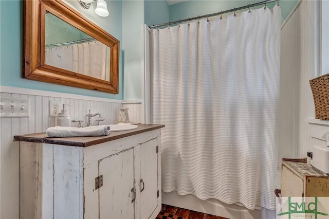 full bathroom with wainscoting and vanity