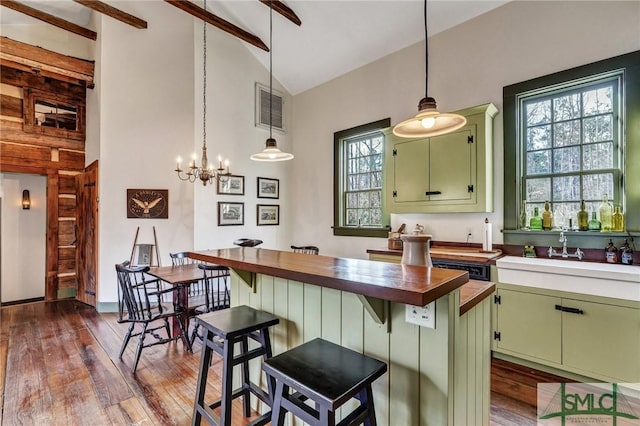 kitchen featuring butcher block counters, visible vents, green cabinets, and a sink