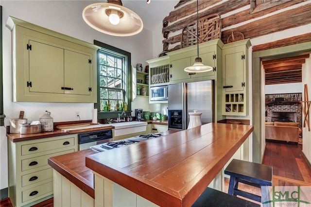 kitchen featuring dark wood finished floors, green cabinets, appliances with stainless steel finishes, a sink, and butcher block countertops