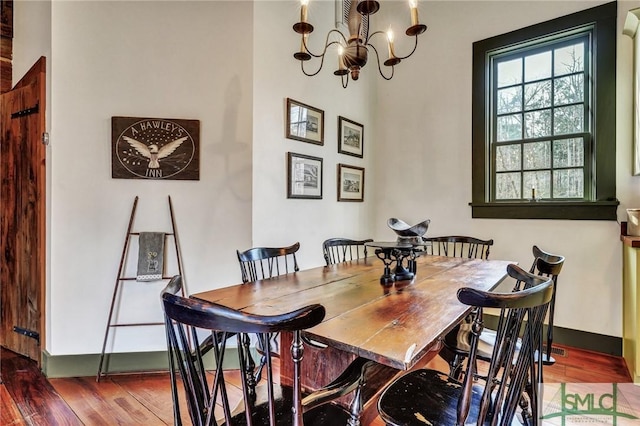 dining space with a chandelier, baseboards, and wood finished floors