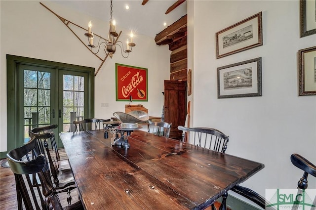 dining room featuring french doors, dark wood finished floors, a towering ceiling, and an inviting chandelier