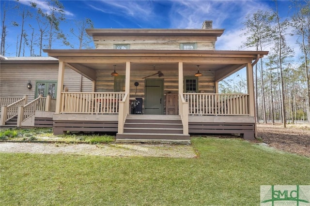 view of front of house featuring french doors, covered porch, a chimney, and a front lawn