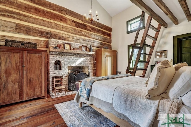 bedroom with beam ceiling, high vaulted ceiling, a brick fireplace, a chandelier, and hardwood / wood-style flooring