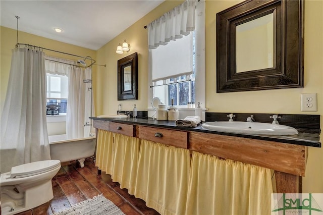 full bathroom featuring toilet, wood finished floors, a sink, double vanity, and shower / bath combo with shower curtain