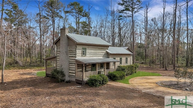 view of front of home with metal roof, a porch, and a chimney