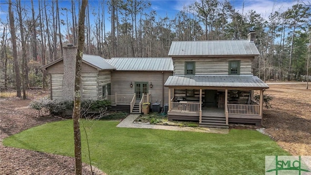 view of front facade featuring a chimney, metal roof, and a front yard